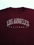 Close-up of letter print graphic and crew neck collar on burgundy sweatshirt